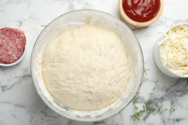 Calzone pizzası yapıyorum. Beyaz mermer sehpada farklı malzemeler var.