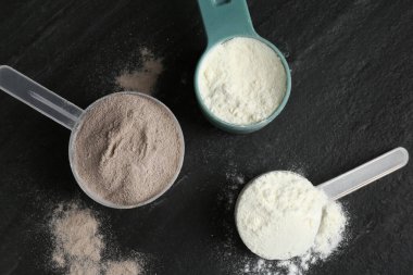 Gri desenli masa üzerinde kepçe kepçe içinde protein tozları, düz uzanma