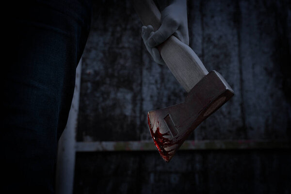 Человек держит окровавленный топор на улице, вид крупным планом