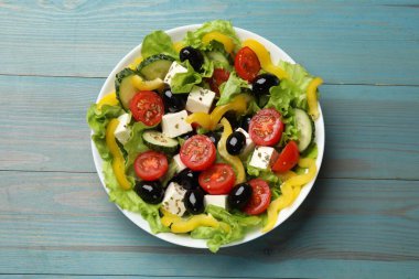 Açık mavi ahşap masada leziz taze Yunan salatası.