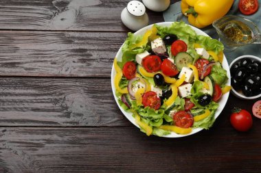 Delicious fresh Greek salad and ingredients on wooden table, flat lay. Space for text