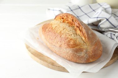 Beyaz ahşap masada bir somun lezzetli ekmek, yakın plan.