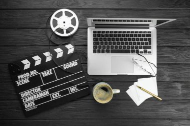 Film alkışı, film makarası, dizüstü bilgisayar ve kahve fincanı siyah ahşap masada, düz yatıyordu.