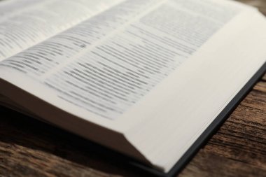 Open Holy Bible in English language on wooden table, closeup clipart