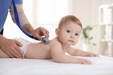 Pediyatrist, klinikte steteskoplu küçük bir çocuğu muayene ediyor. Bebeğin sağlığını kontrol ediyorum.