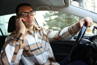 Modern araba kullanırken akıllı telefondan konuşan bir sürücü.