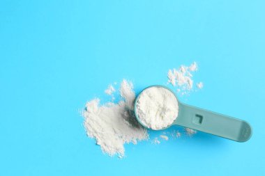 Protein tozu ve açık mavi arka planda kepçe, üst manzara. Metin için boşluk