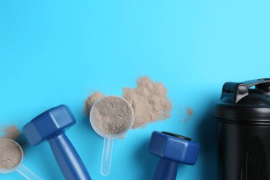 Protein tozu, titretici ve halterler açık mavi arka planda, düz yerde. Metin için boşluk