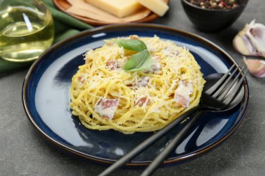 Lezzetli Carbonara makarnası ve gri desenli masada çatal bıçak takımı, yakın plan.
