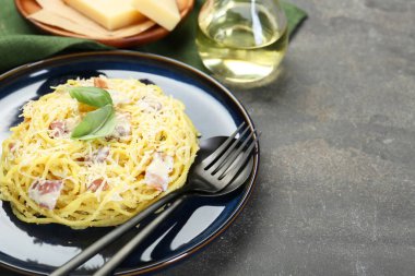 Lezzetli Carbonara makarnası ve gri desenli masada çatal bıçak takımı, yakın plan. Metin için boşluk