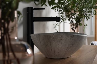 Eucalyptus branches near vessel sink on bathroom vanity. Interior design