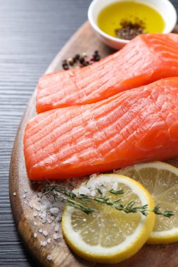 Siyah masada kekik, limon, yağ ve baharatlı taze somon parçaları, yakın plan.