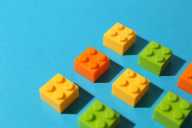 Construction toy. Colorful building bricks on light blue background, closeup. Space for text