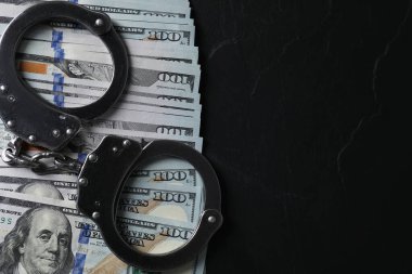Yozlaşma. Kelepçe ve dolar banknotları siyah masa, üst manzara. Metin için boşluk