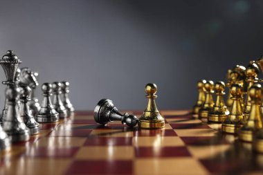 Düşen gümüşe yakın altın piyon ve satranç tahtasındaki diğer taşlarla gri arka plan, yakın plan. Rekabet konsepti