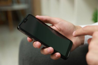 Akıllı telefon kullanan bir adam kapalı alanda boş ekran kullanıyor.