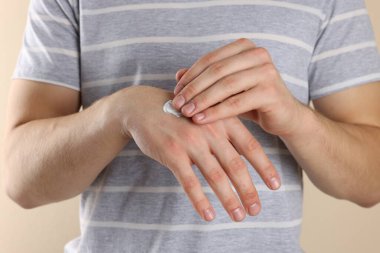 Bej arka plana el kremi süren adam, yakın plan.