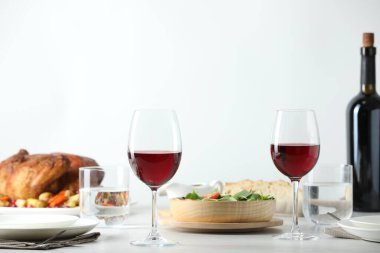 Red wine and delicious dinner served on light table clipart