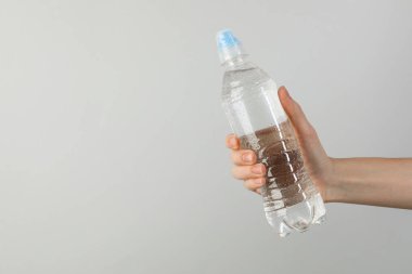 Arka planda plastik su şişesi tutan kadın, yakın plan. Metin için boşluk