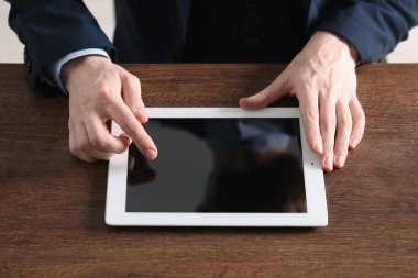 İşadamı ahşap masada tablet kullanıyor, yakın plan. Modern teknoloji