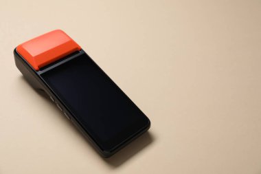 Bej arka planda bir ödeme terminali, yakın plan. Metin için boşluk