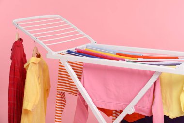 Açık pembe arka planda temiz çamaşırları olan kuru askı, yakın plan.