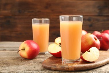 Bardakta lezzetli elma suyu ve ahşap masada taze meyveler, yakın plan.