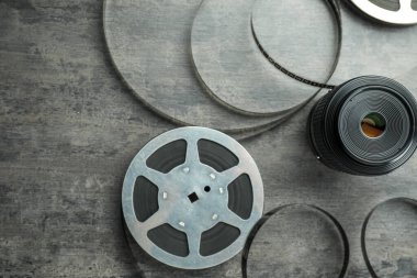 Gri desenli masa üzerinde film makarası ve kamera lensi, düz.