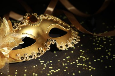 Güzel bir karnaval maskesi, koyu arkaplanda kurdele ve konfeti, yakın plan.