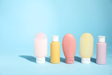 Açık mavi arka planda farklı cilt bakım ürünleri şişeleri