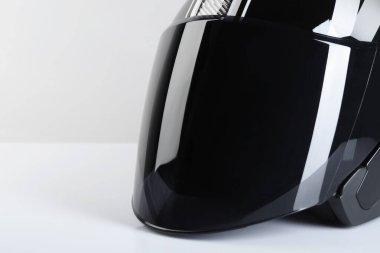 Işık arka planında güneşliği olan modern motosiklet kaskı, yakın plan. Metin için boşluk