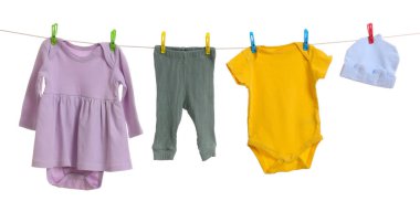 Different baby clothes drying on laundry line against white background