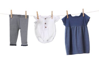 Different baby clothes drying on laundry line against white background