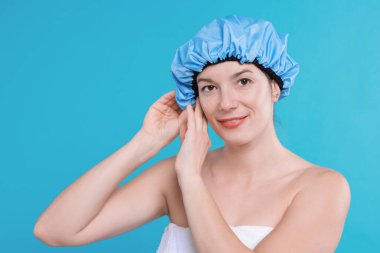 Woman wearing shower cap on light blue background clipart