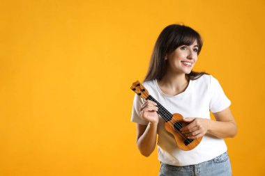 Turuncu arka planda ukulele çalan mutlu kadın, metin için boşluk