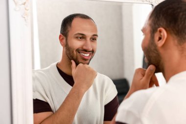 Gülümseyen adam evde aynaya bakıyor.