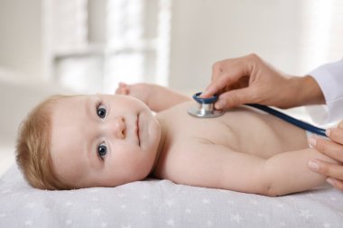 Pediyatrist, klinikte steteskoplu küçük bir çocuğu muayene ediyor. Bebeğin sağlığını kontrol ediyorum.