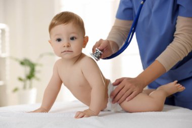 Pediyatrist, klinikte steteskoplu küçük bir çocuğu muayene ediyor. Bebeğin sağlığını kontrol ediyorum.