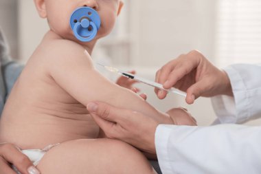 Pediyatrist klinikte bebek aşılıyor.