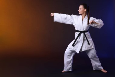 Kimonolu genç kadın karanlık arka planda karate çalışıyor, mesaj için yer var.