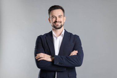 Gri arka planda çapraz kollu gülümseyen bankacının portresi