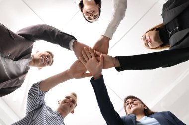 Takım çalışması. Bir grup insan kapalı alanda el ele tutuşuyor.