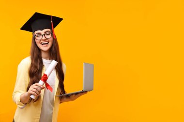Mezuniyetten sonra bilgisayar ve diploması olan mutlu bir öğrenci. Metin için boşluk