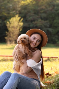 Sonbahar parkında sevimli köpeğiyle gülümseyen kadın.