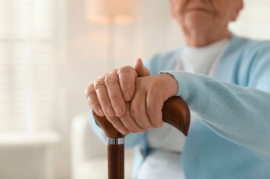Kapalı alanda bastonlu yalnız yaşlı kadın, yakın plan. Metin için boşluk