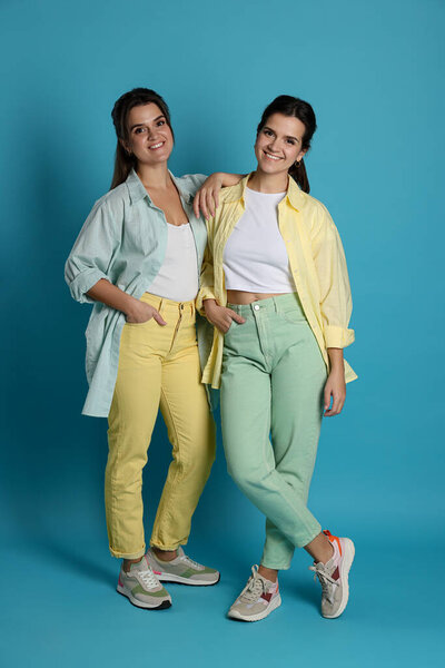 Portrait of beautiful twin sisters on light blue background