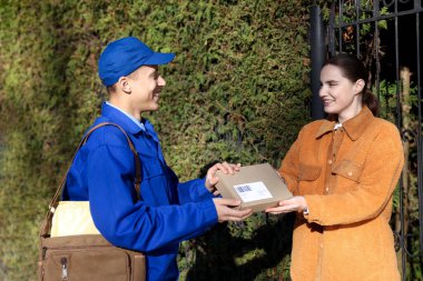 Dışarıdaki postacıdan paket alan bir kadın. Posta servisi