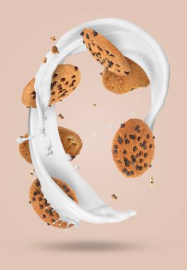 Çikolata parçalı kurabiyeler ve bej arka planda havaya süt sıçratma