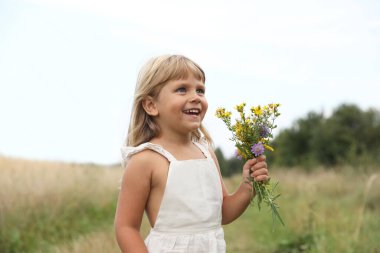 Meadow 'da çiçekli şirin bir kız. Çocuk güzel doğanın tadını çıkarıyor