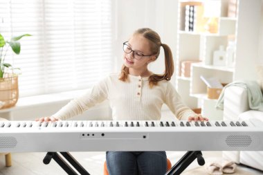 Evde sentezleyici oynayan tatlı bir kız. Elektronik müzik aleti